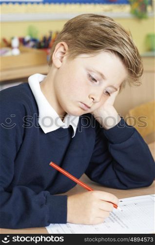 Bored Male Elementary School Pupil At Desk