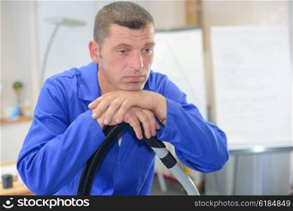 Bored man leaning on vacuum