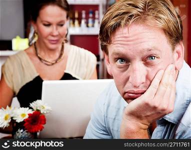 Bored man with woman on laptop computer