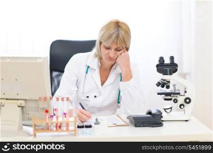 Bored senior doctor woman working at office