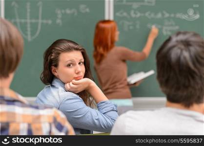 Bored student girl during math lesson sitting front of chalkboard