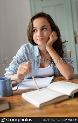 Bored teenage student girl studying at home looking away