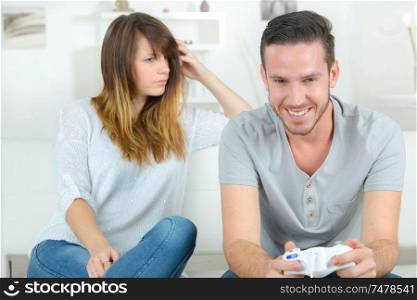 bored woman looking at her boyfriend playing video game