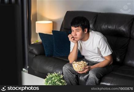 bored young man watching TV on sofa at night