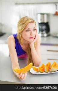 Bored young woman eating slice of melon