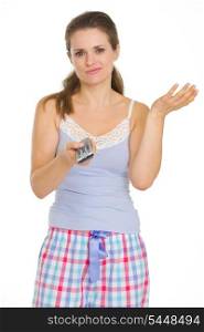 Bored young woman in pajamas holding TV remote control