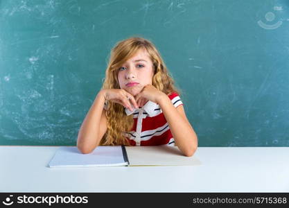 Boring sad expression student schoolgirl on classroom desk at school green chalk board