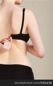 Bosom concept. Slim attractive woman taking off or putting on her black bra rear view. Woman dressing up her bra rear view