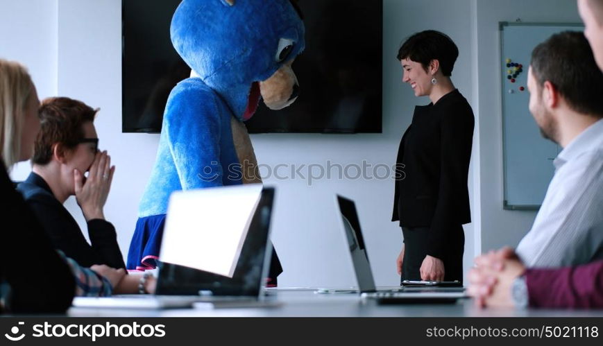 Boss dresed as teddy bear having fun with bussines people in modern corporate office