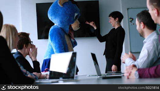 Boss dresed as teddy bear having fun with bussines people in modern corporate office