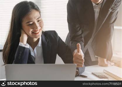 Boss/ manager male employer admires young Asian lady secretary by thumb up for her success and good. Asia Business woman sitting smiling face in the office