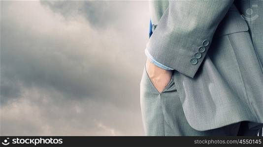 Bossy businessman. Close up of confident businessman with hands in pockets