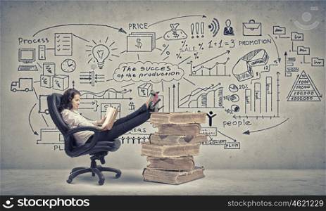Bossy businesswoman in chair. Young businesswoman sitting in chair with her legs on pile of books