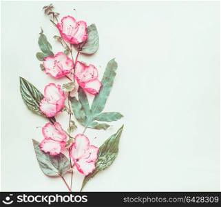 Botanical creative layout with pink flowers and leaves on light green background, top view, copy space