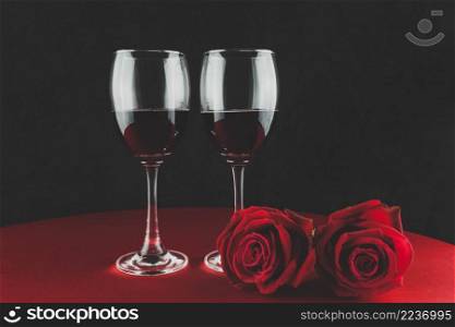 botella de vino con dos copas y una rosa encima de una mesa