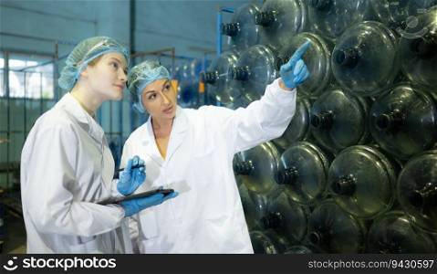 Both of fema≤quality control workers in a drinking water factory Inspecting the quality of water tanks before importing the drinking water be<∫o the tank