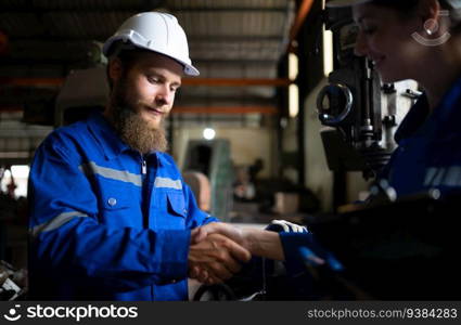 Both of mechanical engineers are checking the working condition of an old machine that has been used for some time. In a factory where natural light shines onto the workplace