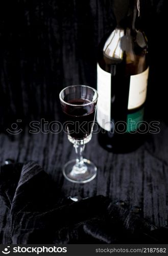 bottle and a glass of red wine on a black background. bottle and a glass of red wine on a black background.