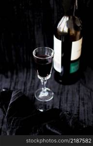 bottle and a glass of red wine on a black background. bottle and a glass of red wine on a black background.