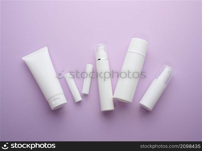 bottle and empty white plastic tubes for cosmetics on a purple background. Packaging for cream, gel, serum, advertising and product promotion, mock up