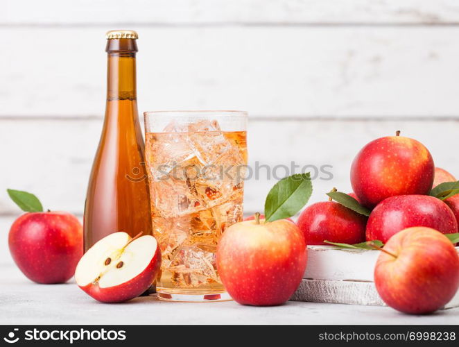 Bottle and glass of homemade organic apple cider with fresh apples in box on wooden background, Glass with ice cubes