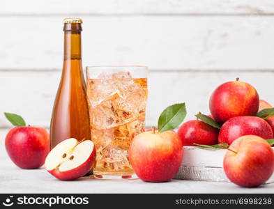 Bottle and glass of homemade organic apple cider with fresh apples in box on wooden background, Glass with ice cubes