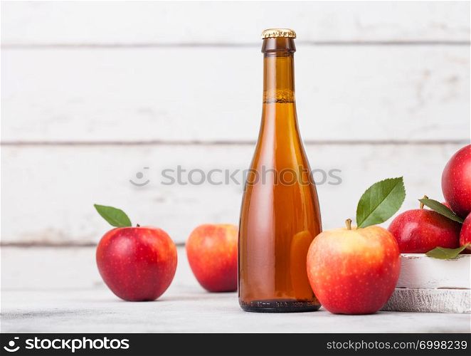Bottle and glass of homemade organic apple cider with fresh apples in box on wooden background, Glass with ice cubes