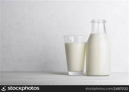 Bottle and glass of milk on white wooden table background with white wall as side copy space