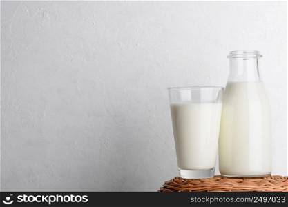 Bottle and glass of milk on wicker basket and white wall background