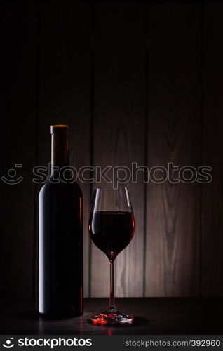 Bottle and glass of red wine on a wooden background. Bottle and glass of red wine on wooden background
