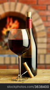 bottle and glass of red wine on the background of the rural fireplace