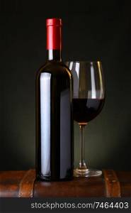 Bottle and glass of red wine standing on a wooden box