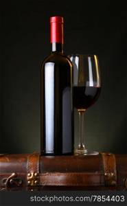 Bottle and glass of red wine standing on a wooden box