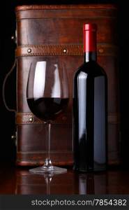 Bottle and glass of red wine with a wooden box in the background