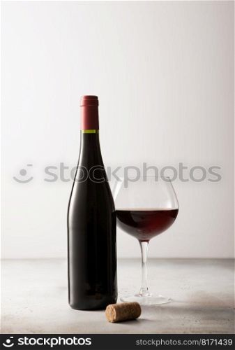 Bottle and glass of red wine with cork on light background. Close up.