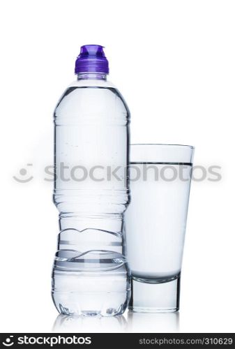 Bottle and glass of still healthy mineral water on white background with reflection