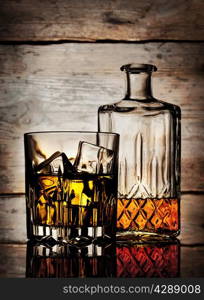 Bottle and glass of whiskey on a wooden background