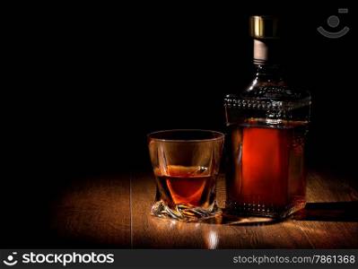 Bottle and glass of whiskey on a wooden table
