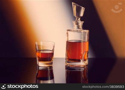 bottle and glass of whiskey on gradient background