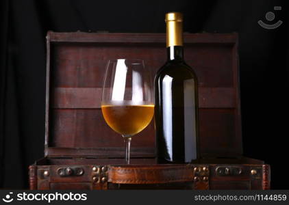 Bottle and glass of white wine in a wooden case