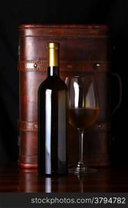 Bottle and glass of white wine with a wooden case in the background