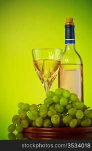 bottle and glass of wine, grape bunch, green background