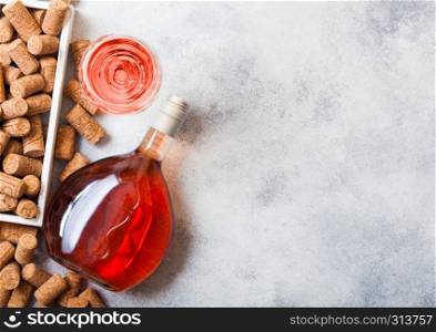 Bottle and glasses of pink rose wine with box of corks on stone kitchen table background. Top view.
