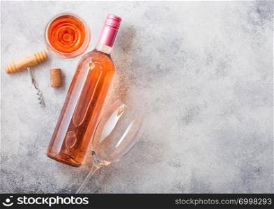 Bottle and glasses of pink rose wine with cork and corkscrew opener on stone kitchen table background. Top view.