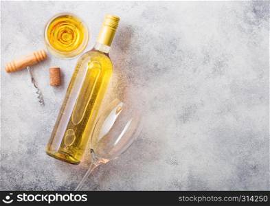 Bottle and glasses of white wine with cork and crkscrew opener on stone kitchen table background. Top view.