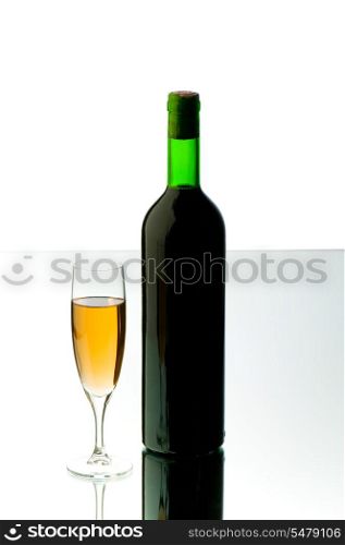 Bottle and wine glass on reflective background