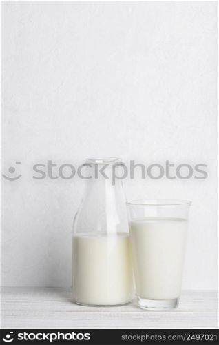 Bottle ang glass of milk on white wooden table background vertical with copy space