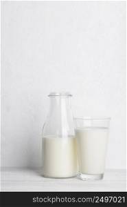 Bottle ang glass of milk on white wooden table background vertical with copy space