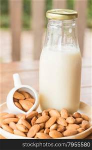Bottle of almond milk on wooden table, stock photo