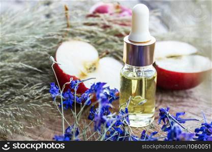 Bottle of apple essential oil and fresh apples on a wooden table. Essential oil is used to fill lamps, perfumes and in cosmetics. Close-up.. Bottle of apple essential oil and fresh apples on a wooden table. Essential oil is used to fill lamps, perfumes and in cosmetics.